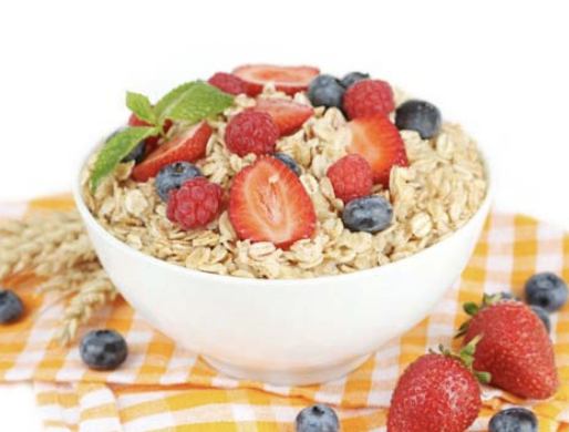 Bowl of oats topped with strawberries, blueberries, and a piece of mint for garnish.