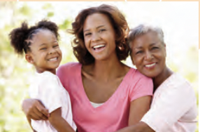 Three women smiling at a camera, a little girl, her mother, and her grandmother.