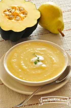 Un tazón de sopa de calabaza suave con jengibre y ajo está cubierto con yogur y perejil picado.