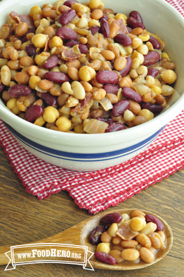 A mixture of seasoned beans and bacon is shown in a serving bowl.