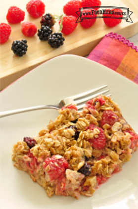 Se muestra un trozo de avena horneada especiada con jugosas moras y frambuesas en un plato.