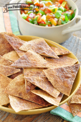 Chips de tortilla espolvoreados con canela se muestran en un plato con un tazón de salsa de durazno.