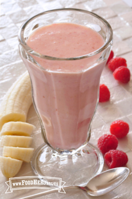 Un licuado cremoso rosado de plátano y frambuesa se muestra en un vaso para servir.