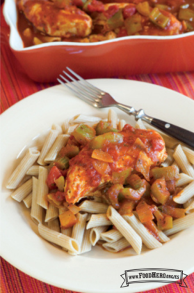 Pollo tierno cocinado en salsa de tomate y especias servido sobre un plato de pasta.