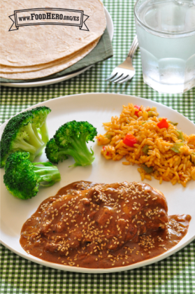 Pollo con una salsa espesa y sabrosa espolvoreado con semillas de ajonjolí y servido con arroz y brócoli en un plato.  