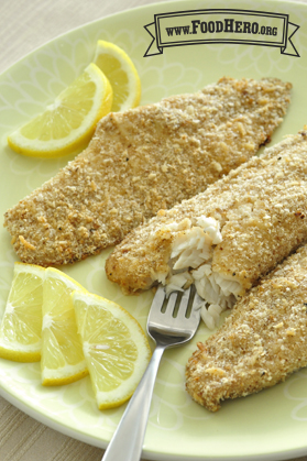 Plate of breaded, flakey white fish with slices of lemon.