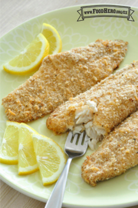 Plato de pescado blanco empanizado con rodajas de limón amarillo.