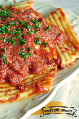 Plato de pasta rellena de queso con salsa roja y perejil fresco.