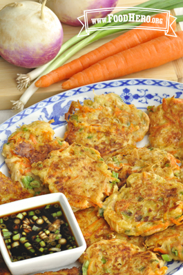 Plate of crispy vegetable pancakes with dipping sauce.