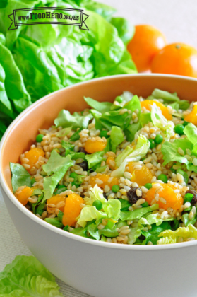 Tazón de ensalada de mandarina y cebada con un tenedor de madera.