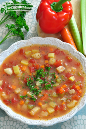 Tazón de sopa con verduras en cubitos y pescado cubierto con perejil.