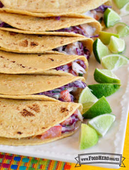  Plato de tortillas de maíz con relleno cremoso de repollo y pescado servido con rodajas de limón.