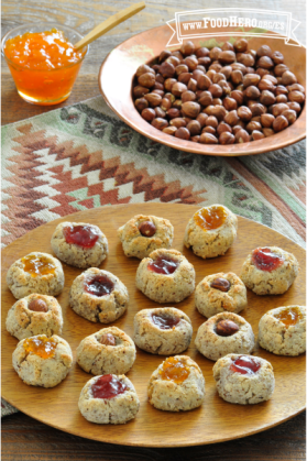 Plato de galletas del tamaño de un bocado con un centro de mermelada pegajosa.