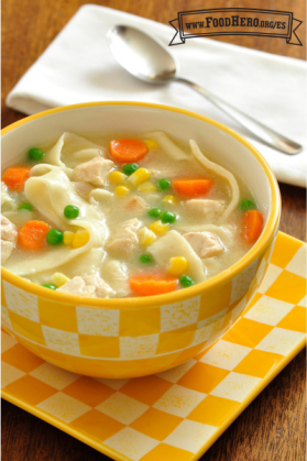 Tazón de sopa de pollo y fideos servida con galletas saladas.