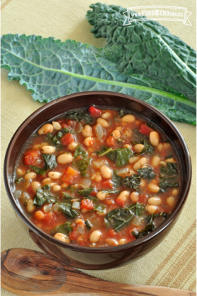 Tazón de sopa con base de tomate, col rizada y frijoles.