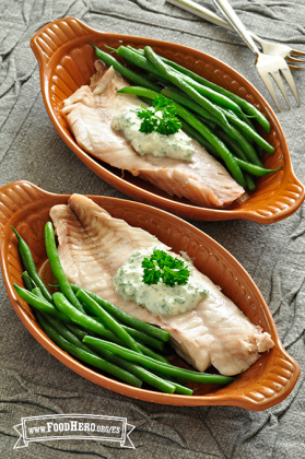 Tazones con filetes de pescado acompañados con ejotes y una salsa cremosa.