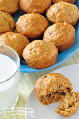 Panecillos (muffins) dorados con pasas servidos con un vaso de leche.