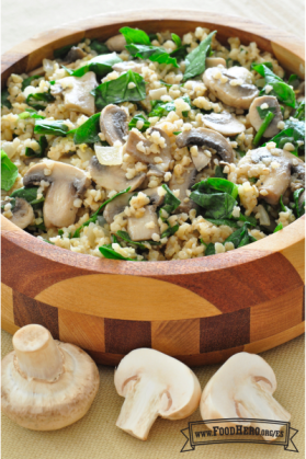 Un tazón de madera con trigo bulgur, hongos y espinacas.