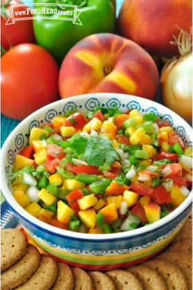 Tazón pequeño de una colorida salsa de durazno y verduras exhibida con galletas saladas.