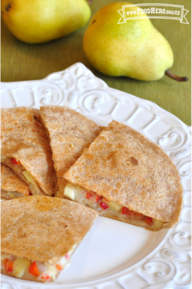 Plato de tortilla dorada doblada sobre un relleno de queso, pera y verduras.