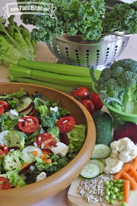 Wooden bowl filled with a variety of raw vegetables.