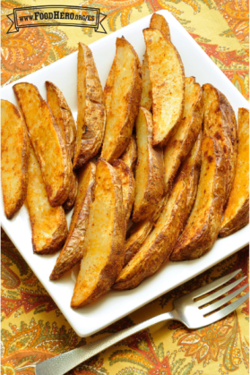 Plato de rebanadas de papa al horno doradas.   