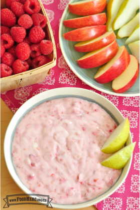 Tazón de dip de frambuesas con yogur servido con rodajas de manzana y pera.