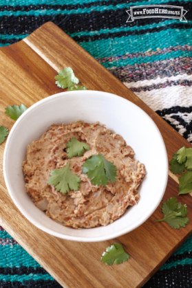 Tazón pequeño de frijoles machacados adornados con cilantro.