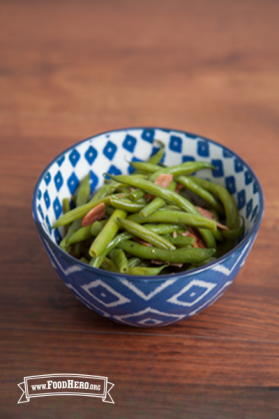 Bowl of green beans with ham and onions.