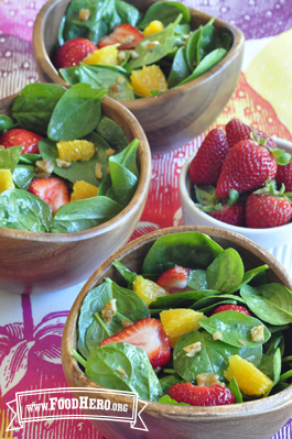 Bowls of spinach salad topped with strawberries and orange slices. 