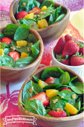 Tazones con ensalada de espinacas cubiertas con fresas y rodajas de naranja.