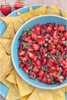 Tazón con salsa de fresa de color verde brillante y rojo servida con chips de tortilla.