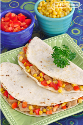 Plato con tortillas dobladas sobre una mezcla de atún, verduras y queso.