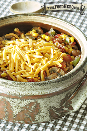 Bowl of chili topped with shredded cheddar cheese.