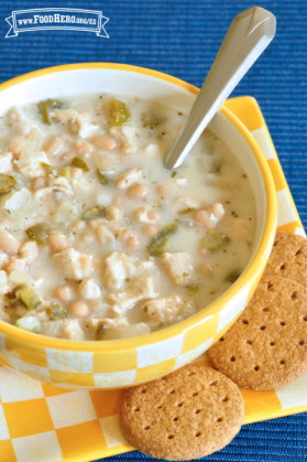 Tazón pequeño con sopa cremosa de pollo y frijoles servida con galletas saladas.