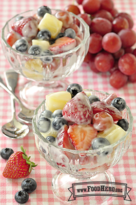 Footed dessert glasses filled with a fruit mix coated in yogurt.