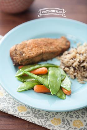 Baby carrots and snow peas on a plate with rice and fish.