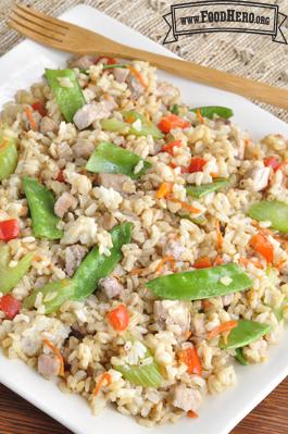 Colorful plate of sautéed rice, pork and vegetables with a soy sauce glaze.