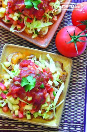 Small plates of baked potato slices topped with lettuce, salsa and cilantro.