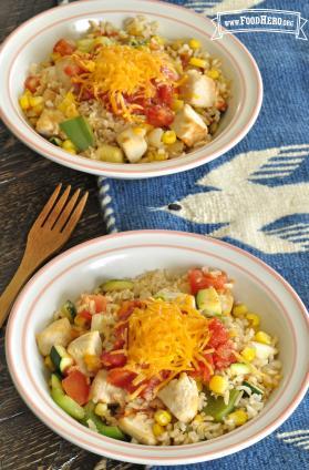 Bowls of rice, vegetables and chicken with shredded cheese.