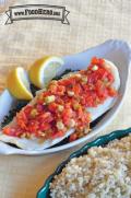 Fish filet on a spinach bed with a layer of tomato and green onion.