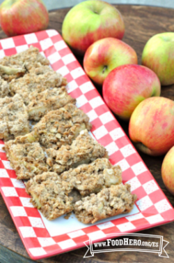 Barritas de Manzana horneadas con avena desmoronada en la parte superior se muestran en un plato.