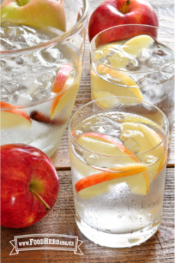 Se muestran vasos de refrescante Agua con Sabor a Manzana y Canela con guarnición de rodajas de manzana.