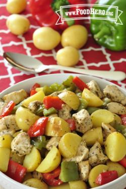 Bowl filled to the brim with baked bite-size potatoes, chicken and bell peppers.