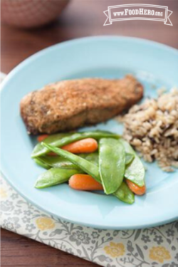 Baby carrots and snow peas on a plate with rice and fish. 