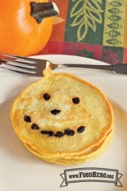 Stack of pumpkin shaped pancakes with raisins. 