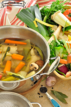 Pot full of water with vegetables and herbs. 