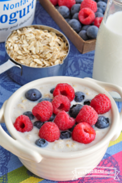 Tazón de cerámica con avena cremosa cubierta con frambuesas y arándanos azules.