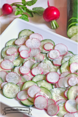 Plato de pepinos y rábanos en rodajas finas con salsa de yogur sazonada.