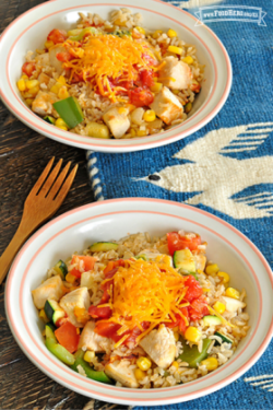 Tazones de arroz, verduras y pollo con queso rallado.